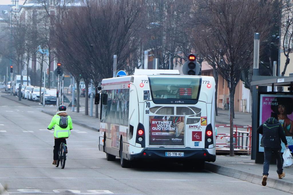 Cycliste à côté d'un bus, portant une veste jaune fluo