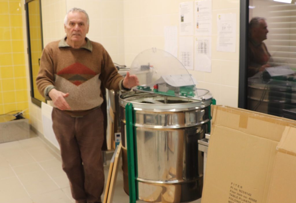 Noël Mallet devant la centrifugeuse de la miellerie