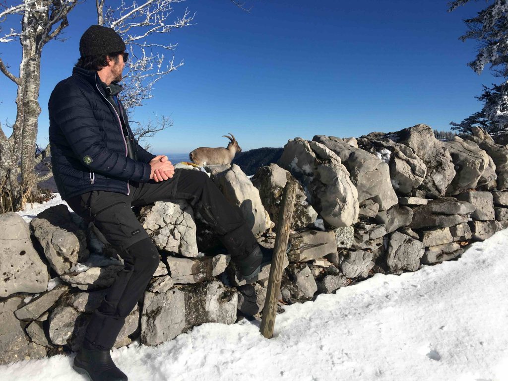Marc assis sur un muret, observe une étagne dans la neige