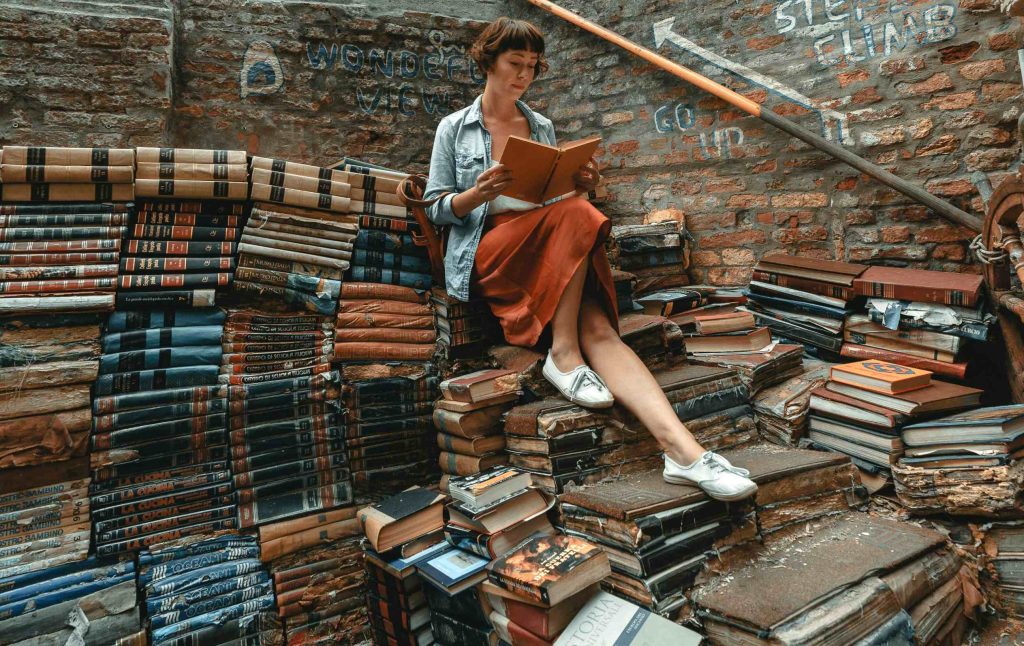 Jeune femme lisant sur une montagne de livres