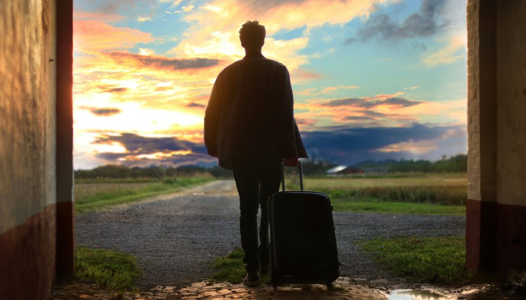 un homme avec une valise allant vers un beau coucher de soleil